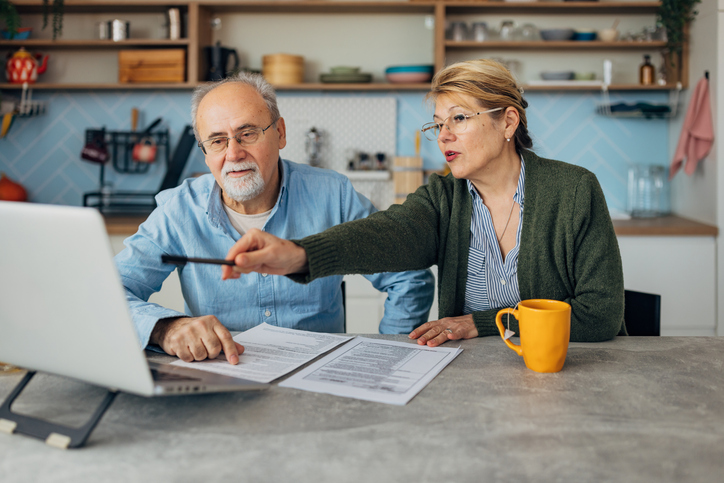 Couple in their sixties reviewing mortgage documents at home
