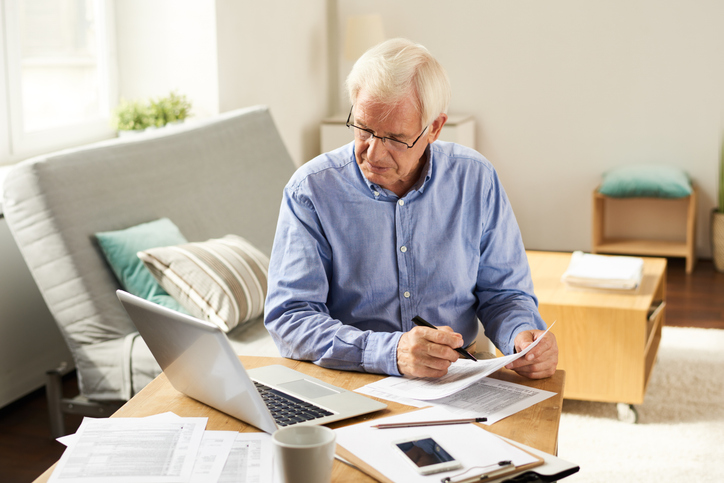 Older man organising property files at a kitchen table