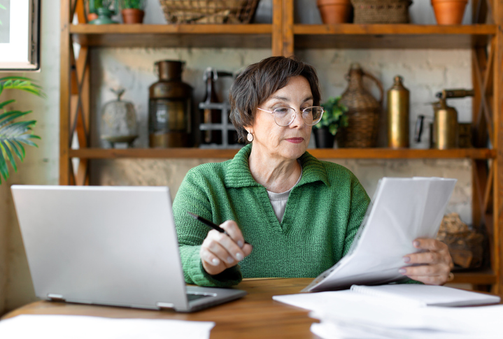 Woman in her sixties reviewing financial documents at a desk